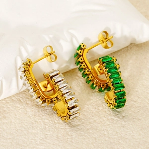 Macro view of C-shape gold earrings with rectangular emerald and white zirconia