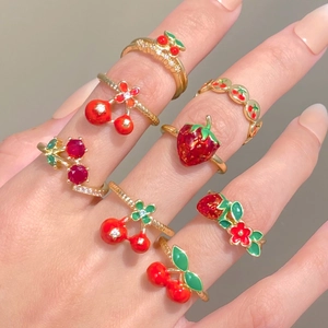 Close-up of golden fruit rings with red strawberry and cherry enamel detailing