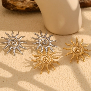 Détail de boucles d'oreilles soleil en finitions or et argent avec centre texturé