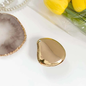 Close-up of golden mango-shaped mirror phone grip with premium metallic reflective finish