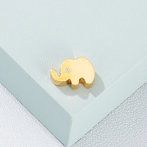 Macro shot of a gold-plated elephant pendant with a sparkling crystal eye on blue base