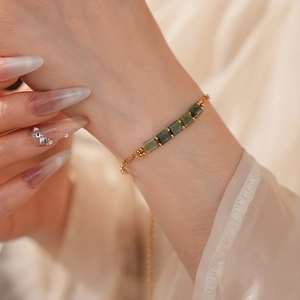 Détail d'un bracelet vintage en chaîne dorée avec pierres vertes sur le poignet