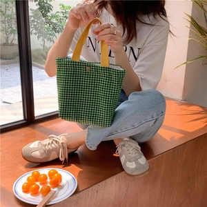 Lifestyle view of a chic green houndstooth wool tote bag with bright yellow handles