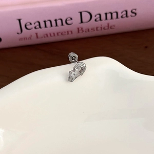 Detail of silver heart ear stud with pink zircon on a white ceramic dish