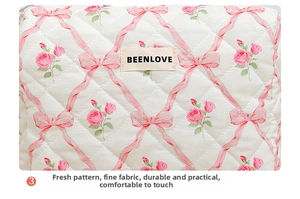 Close-up of quilted floral makeup bag featuring pink rose patterns and brand label