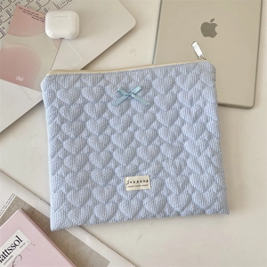 Détail de la housse matelassée à rayures bleues avec motif cœur et décoration nœud