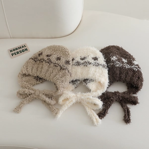 Flat lay of warm plush earflap hats in beige and brown with jacquard patterns