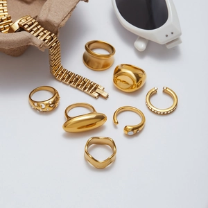 Flat lay of multiple gold-plated stainless steel rings and bracelet with natural stones