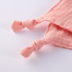 Close-up of soft pink double-layer cotton gauze baby comforter with knotted edge details