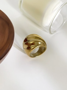 Détail d'une bague large dorée avec texture ondulée 3D et finition polie brillante