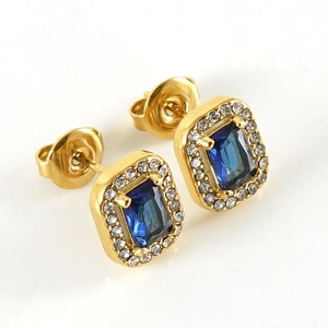 Macro shot of 18K gold earrings featuring a blue rectangular zircon with a diamond halo