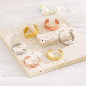 Detail of 18k gold plated geometric C-shape rings on travertine tray with pearls