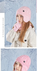 Close-up of pink cable knit winter hat with neck warmer and gloves in snowy setting