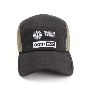 Detail view of contrast stitching and white embroidery on a black and green five-panel cap
