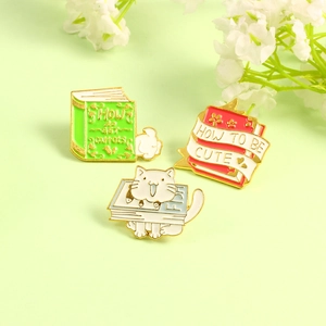 Three enamel cat and bunny book pins including carrot and cute themes on green background
