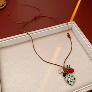 Detail of bohemian wax cord heart pendant with rustic wooden beads and silver cross