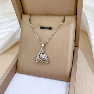 Macro view of silver pumpkin carriage necklace with crystals on a beige velvet box