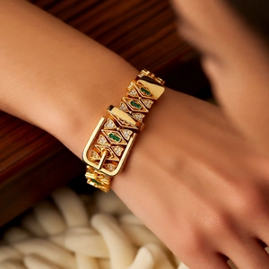 Close-up of 18k gold plated buckle bracelet with emerald stones and crystal inlay