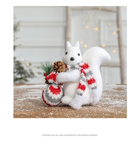 Close-up of a white flocked squirrel ornament with a knitted scarf and pine cone