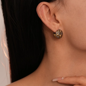 Close-up of a model wearing a vintage gold fleur-de-lis earring with sparkling zircons