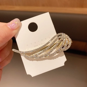 Detailed view of a golden wing hair clip with rhinestones on a white card display