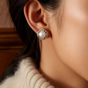 Close-up of a French style pearl earring with gold geometric frame on a model