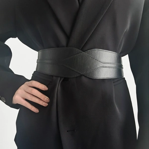 Detail of wide black leather corset belt showing fine stitching on a dark blazer