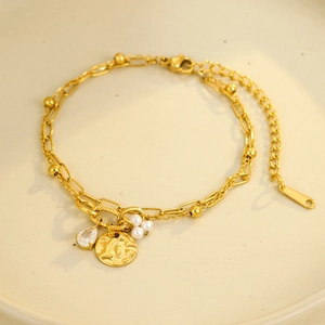 Detail of gold titanium steel double bracelet with water-drop zircon and pearl charms