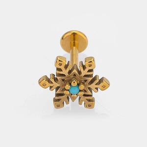 Detailed macro shot of golden snowflake labret stud with a turquoise center stone