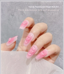 Close-up of 3D pink resin heart nail charms on manicured nails with soft fabric background