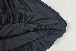 Detail of elastic gathered cuff and pleated black fabric with subtle silk-like luster