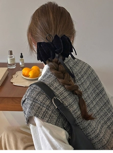 Detail of vintage black velvet bow hair clip with long ribbons worn on model hair