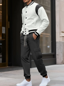 Detail of grey varsity jacket with black sleeves and cargo joggers on street model