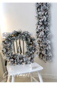 Detail of flocked Christmas wreath and vine with red berries, pine cones and LED lights