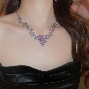 Close-up of elegant silver necklace with purple crystal flower and leaf charms on model