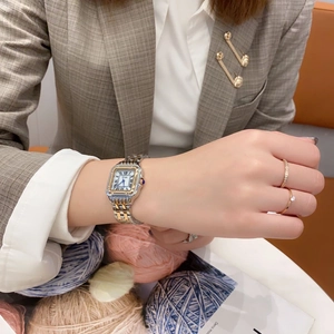 Nahaufnahme der Vintage-Uhr mit römischen Ziffern und zwei Goldringen am Handgelenk