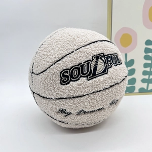 Detail of off-white plush basketball pillow with black stripes and soulful embroidery