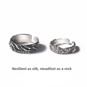 Detail view of retro silver angel and demon couple rings with feather textures