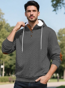 Détails de la texture tricotée en losange du sweat à capuche gris pour hommes avec écussons