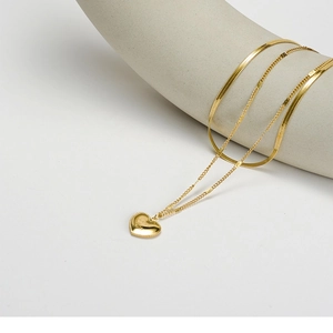 Double-layered gold titanium steel heart pendant necklace on minimalist ceramic display