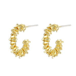 Detailed macro view of gold C-shaped earrings with textured crushed metal finish
