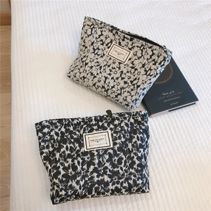 Detailed view of black and white floral quilted makeup bags with Time to Party tags