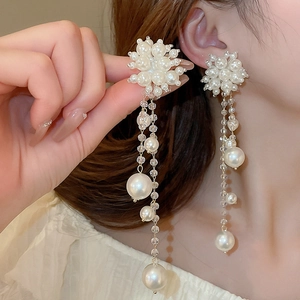 Detail of elegant white pearl tassel earrings with long beaded strands and gold chain