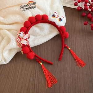 Detail of red festive headband featuring traditional lion dance and long silk tassels