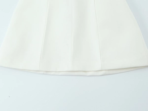 Detailed close-up of the woven fabric texture and hem stitching on a white mini dress