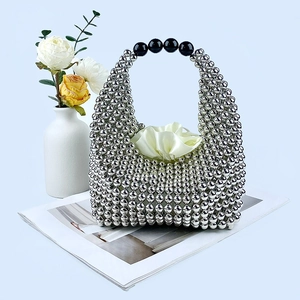 Detail of silver beaded pillow bag featuring large black beads on the handle with white lining