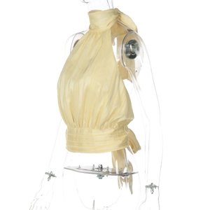 Detail of light yellow pleated halter top showing neck ties and ruched waist texture