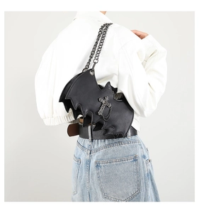 Detail of black gothic bat bag with metallic cross and chunky chain strap on a model