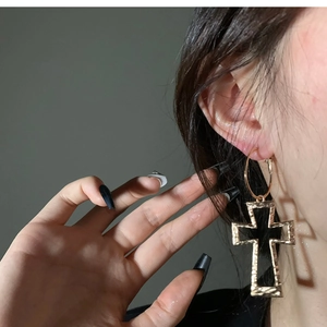 Fashionable gold cross hoop earrings with hammered texture worn by a female model