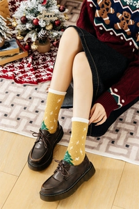 Detail of warm yellow double-sided plush Christmas socks with festive tree patterns